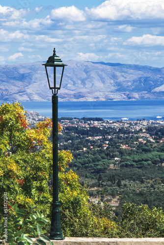 Panoramablick in Pelekas Korfu, mit einer dekorativen Straßenlaterne links seitlich im Bild, vertikal 