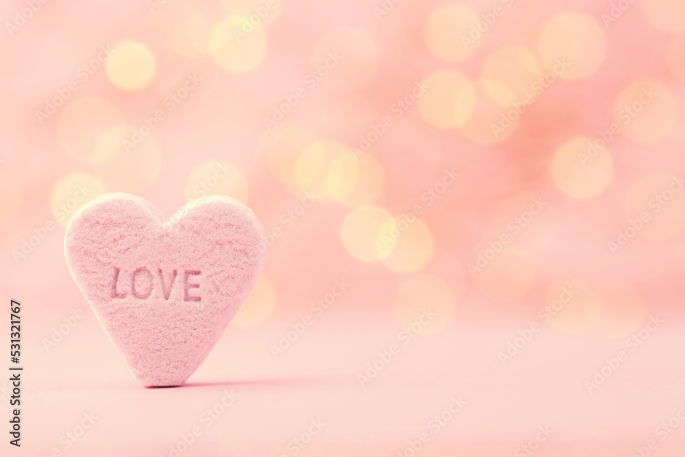 Pastel colored candy hearts in a bokeh background.