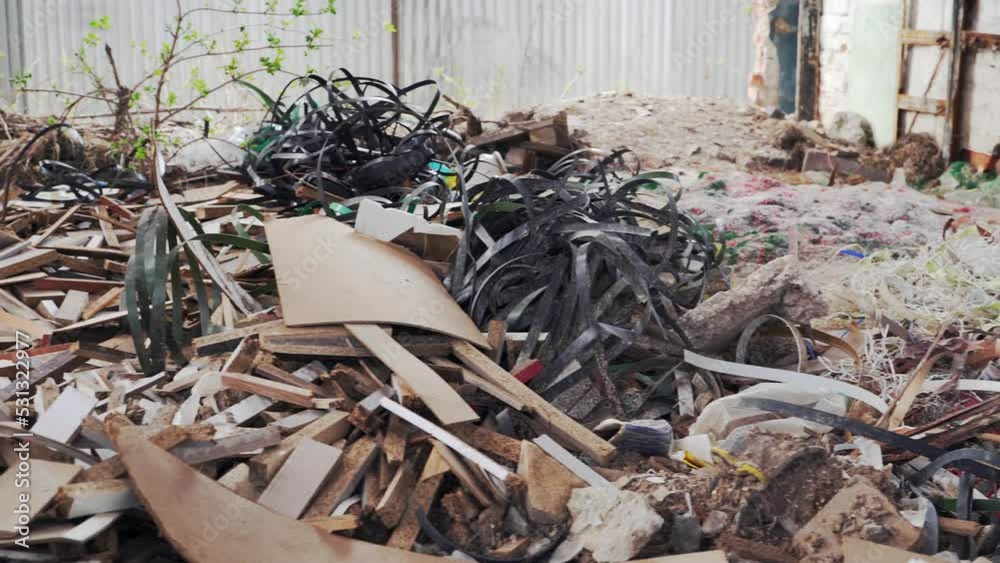 Production waste in the yard. Heaps of rubbish, chipboard fragments, plastic bands. Environmental pollution.