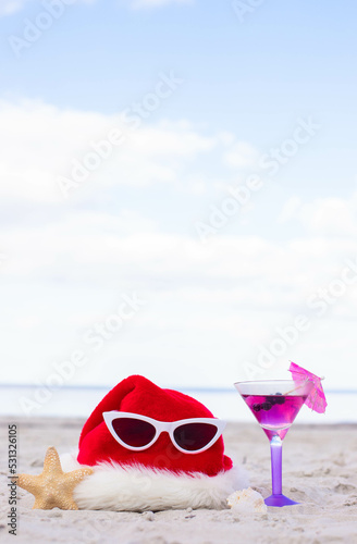 Christmas background Santa Claus hat on the beach with starfish,cocktail and sunglases