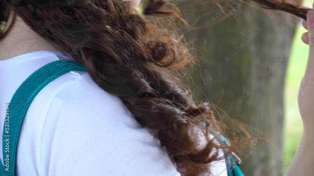 Young woman in white t-shirt and blue sundress touching her hair. Close-up. Young woman in white t-shirt and blue sundress touching her hair. Close-up.