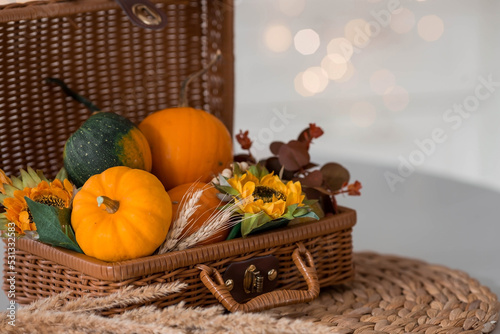 Home warmth. Still-life. Pumpkins, a wicker basket, candles and flowers. In the background is the interior of a white Scandi-style kitchen. The concept of home and comfort. Autumn decor for Halloween.