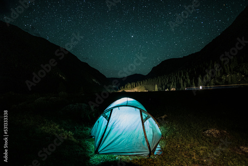 The tent stands against a night sky of stars and mountains