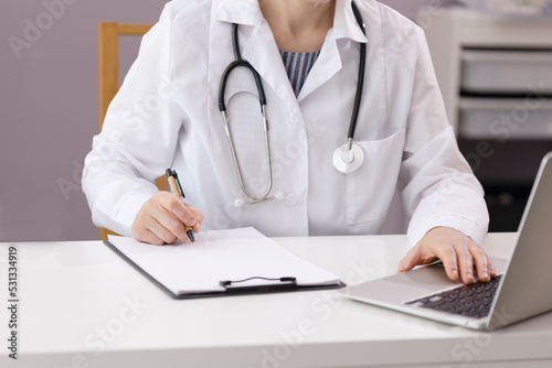 The doctor works in his office  sees patients and takes notes. The doctor works at the computer in the hospital. Medical photo with copy space. High quality photo