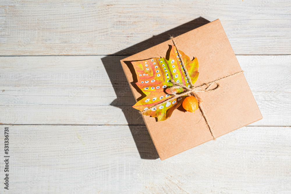 Obraz premium Craft gift box decorated autumn maple leaf. Thanksgiving day