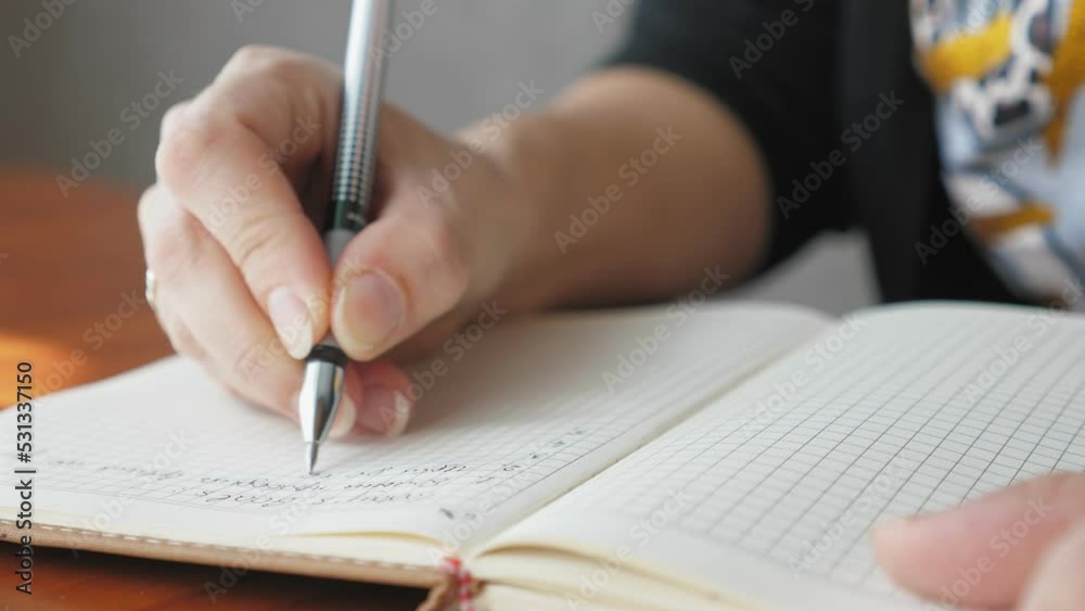 A woman writes with a pen in a notebook, close-up. The girl makes a to-do list for the day. Caucasian woman writes goals today. A woman writes with a pen in a notebook, close-up. The girl makes a to-do list for the day. Caucasian woman writes goals today.