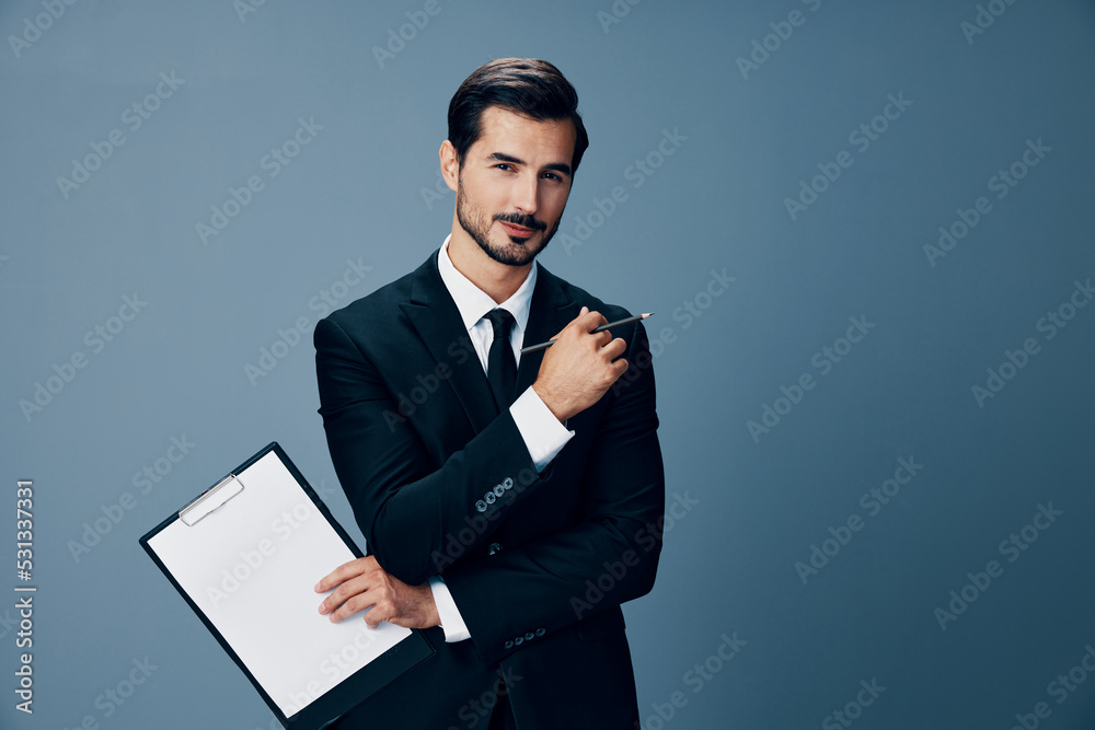 Portrait of a business man in a stylish suit smile with tie beautiful face on a blue isolated background with a tablet in his hands. Business concept young businessman startup copy place Portrait of a business man in a stylish suit smile with tie beautiful face on a blue isolated background with a tablet in his hands. Business concept young businessman startup copy place