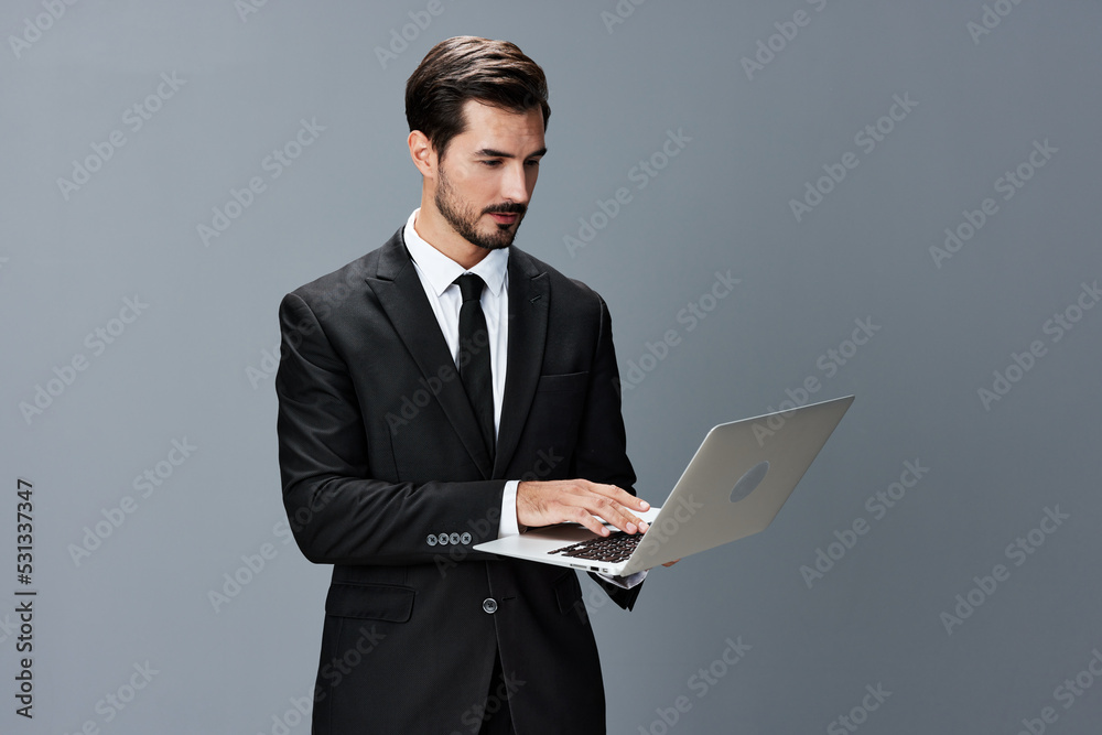 Man business tired stressed out looking at his laptop and working online via internet in business suit video call business talks on gray background copy place Man business tired stressed out looking at his laptop and working online via internet in business suit video call business talks on gray background copy place