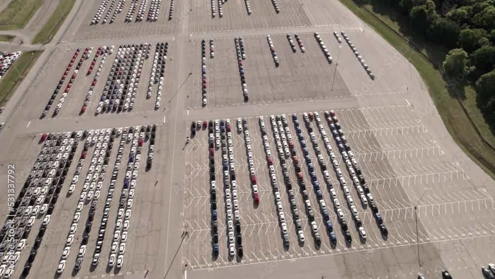Parked new cars at the car automotive plant manufacturer lot. Electric hybrid cars vehicle factory. Aerial. Almost empty stock. Broken supply chain and chip shortage lead to car shortage availability Parked new cars at the car automotive plant manufacturer lot. Electric hybrid cars vehicle factory. Aerial. Almost empty stock. Broken supply chain and chip shortage lead to car shortage availability