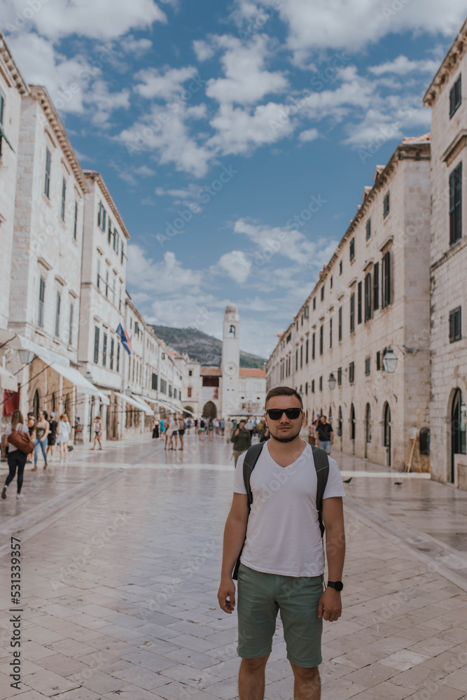 Dubrovnik, Croatia - September 21, 2021: Man tourist, traveler walks along Placa, the Main Street. Old town was listed as UNESCO World Heritage Sites in 1979 in Europe. primary promenade is Stradun