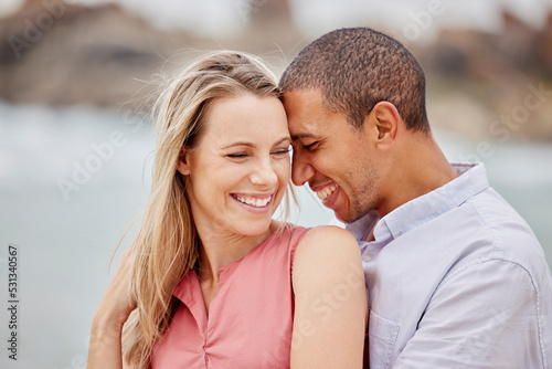 Love, happy and hug with couple together for romance, relationship and lifestyle on beach holiday trip. Happiness, care and support with man and woman in embrace on summer vacation date by the sea