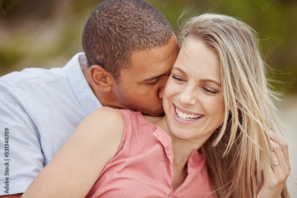 Happy interracial couple, love and smile for relationship together in nature happiness and outdoors. Man and woman smiling in joyful marriage, neck kiss and bonding time outside on holiday vacation