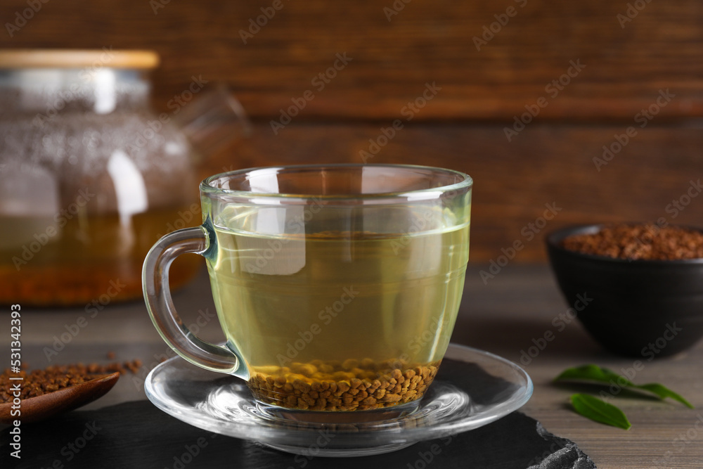 Freshly made buckwheat tea in glass cup on wooden table, closeup Freshly made buckwheat tea in glass cup on wooden table, closeup