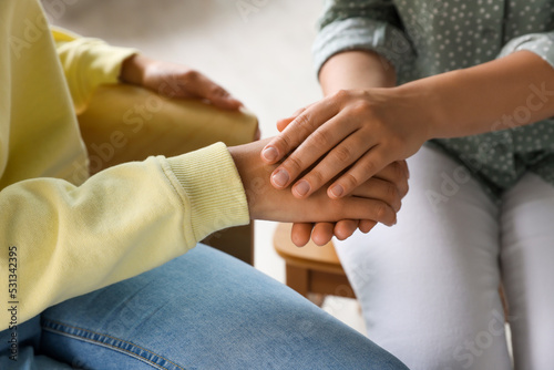 Psychotherapist holding patient's hand in office, closeup