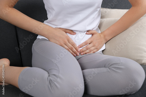 Woman suffering from cystitis on sofa at home, closeup © New Africa