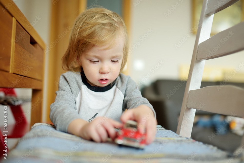 Cute toddler boy playing with red toy car. Small child having fun with toys. Kid spending time in a cozy living room at home. Cute toddler boy playing with red toy car. Small child having fun with toys. Kid spending time in a cozy living room at home.
