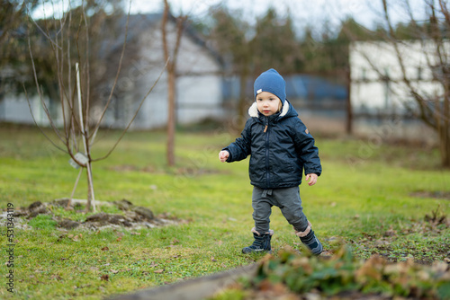 Funny toddler boy having fun outdoors on chilly winter day. Child exploring nature.