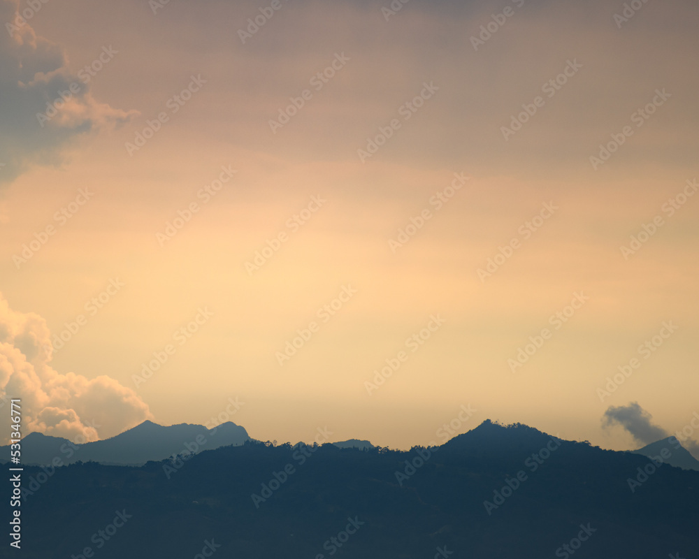 Obraz premium Yellow and blue Sunset landscape with light clouds. Atarcdecer azul y amarillo con leves nubes.