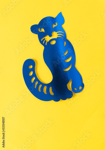 Fototapeta Naklejka Na Ścianę i Meble -  blue metallic foil paper silhouette of a big cat (tiger or jaguar) isolated on yellow paper
