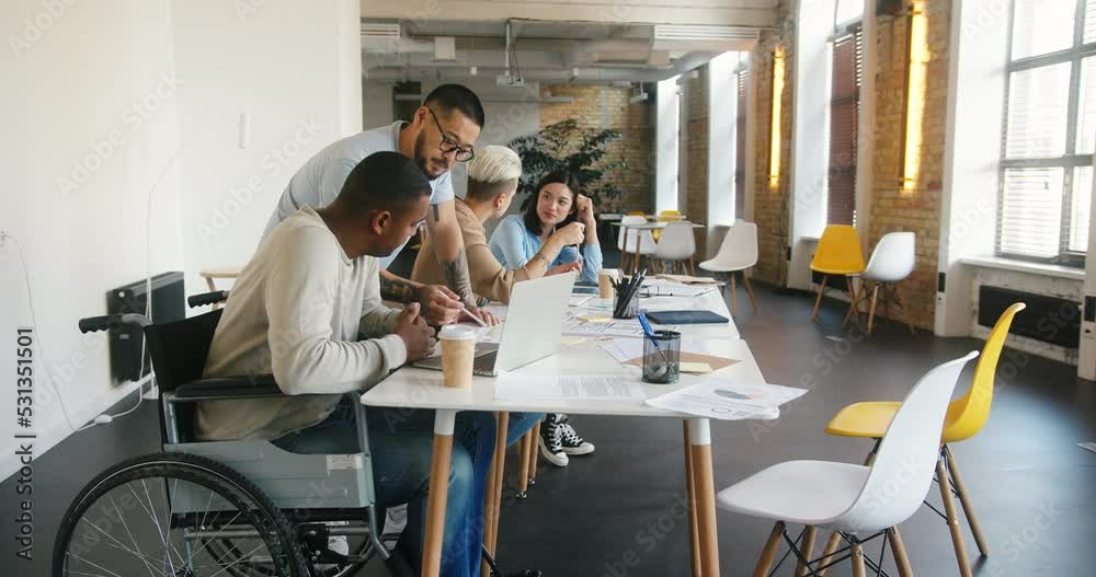 Latin manager explains project plan to man in wheelchair