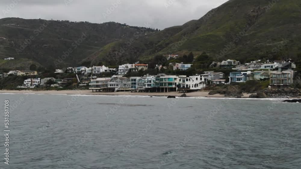 Aerial view of beachfront luxury homes in Malibu with mountain backdrop Aerial view of beachfront luxury homes in Malibu with mountain backdrop