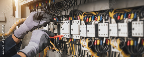 Fotografie, Obraz Electricity and electrical maintenance service, Engineer hand holding AC multimeter checking electric current voltage at circuit breaker terminal and cable wiring main power distribution board
