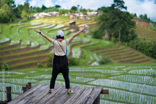 Beautiful Asian tourism women on the balcony of the cottage and lush green rice paddy fields are flooded parcels.