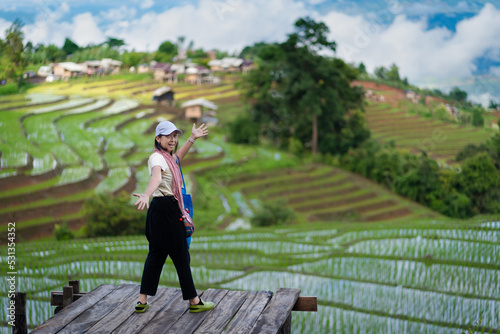 Beautiful Asian tourism women on the balcony of the cottage and lush green rice paddy fields are flooded parcels.