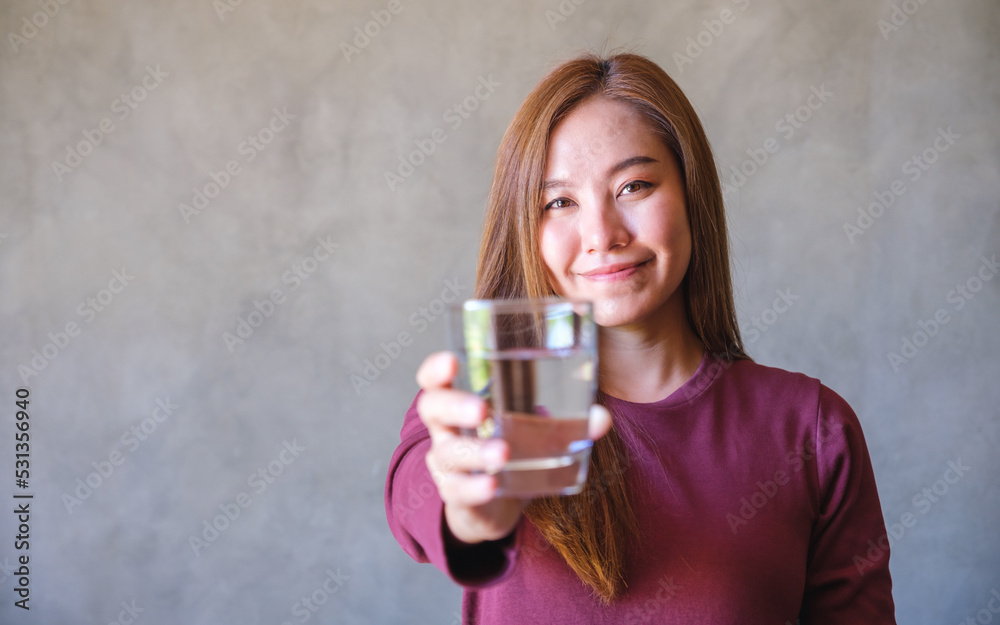 Portrait image of a young woman holding and giving a glass of water Portrait image of a young woman holding and giving a glass of water