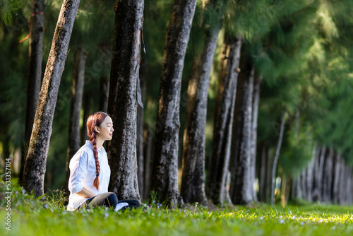 Woman relaxingly practicing meditation in the pine forest to attain happiness from inner peace wisdom for healthy mind and soul concept