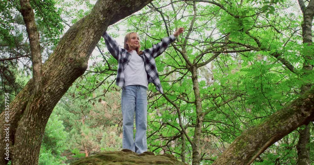 Happy girl with raised arms standing on tree branch. Smiling fearless female enjoying at forest. She is wearing casuals while having fun during weekend in woodland. Happy girl with raised arms standing on tree branch. Smiling fearless female enjoying at forest. She is wearing casuals while having fun during weekend in woodland.