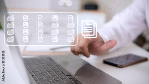 Document Management System (DMS) being setup by IT consultant working on laptop computer in office. Software for archiving, searching and managing corporate files and information