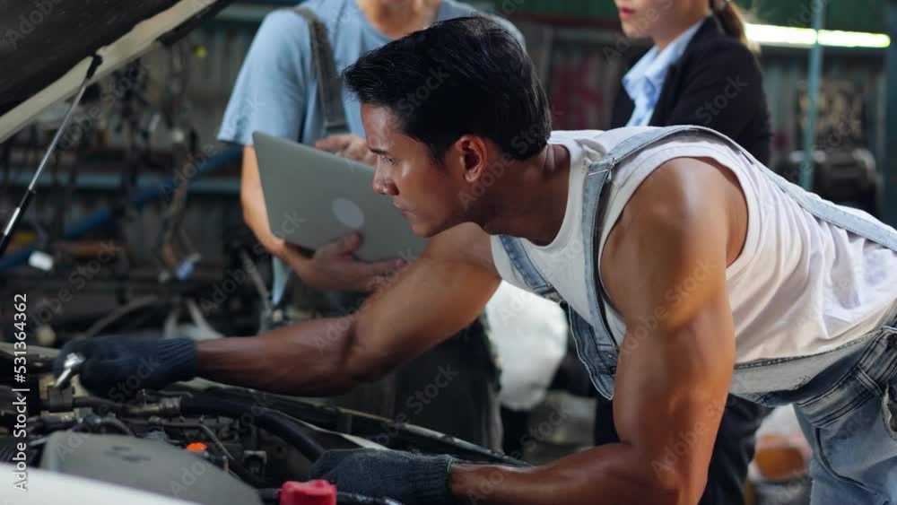 Young male mechanic worker in garage working repair service fix the car engine at old industry car garage workshop. Young male mechanic worker in garage working repair service fix the car engine at old industry car garage workshop.