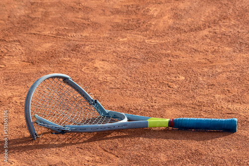 Broken tennis racket on clay tennis court. Mental health problem in sports. Negative emotions, stress, dissatisfaction, defeat, crash, failure, loss concept