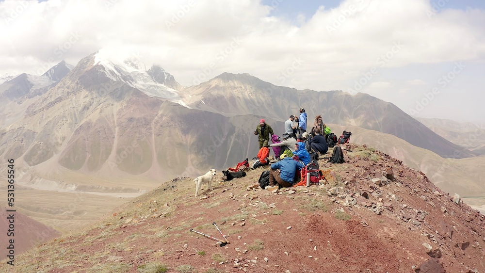 A group of climbers with a dog are resting on the top of the Red Katya Mountain. Beautiful summer mountain landscape.