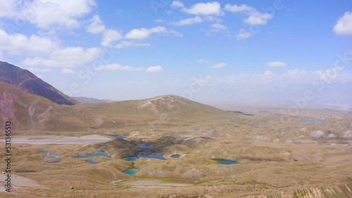 Aerial view of the green valley with blue mountain lakes under Lenin Peak. Beautiful nature of Kyrgyzstan.
