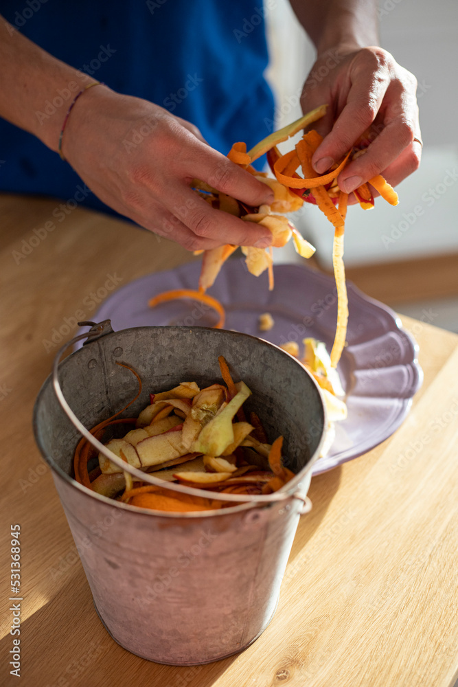 Male hands sorting vegetable peelings in tin bin. Use of food waste