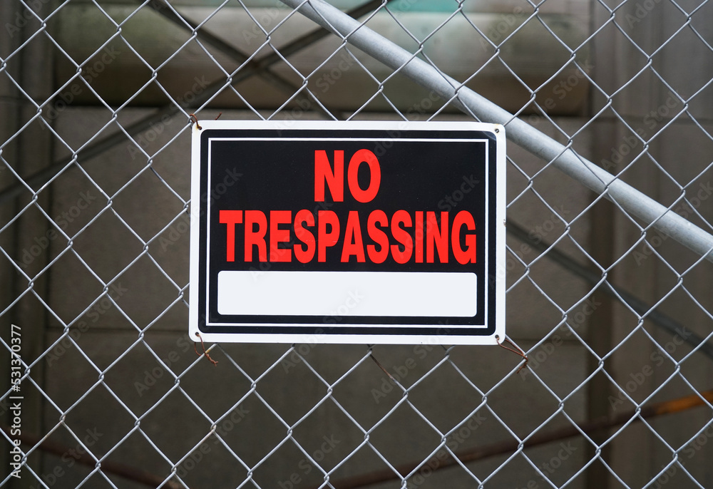 no trespassing warning sign on iron chain link fence