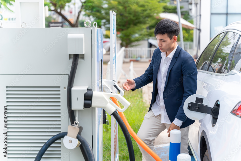 A man attaching power cable to electric car. Electric vehicle