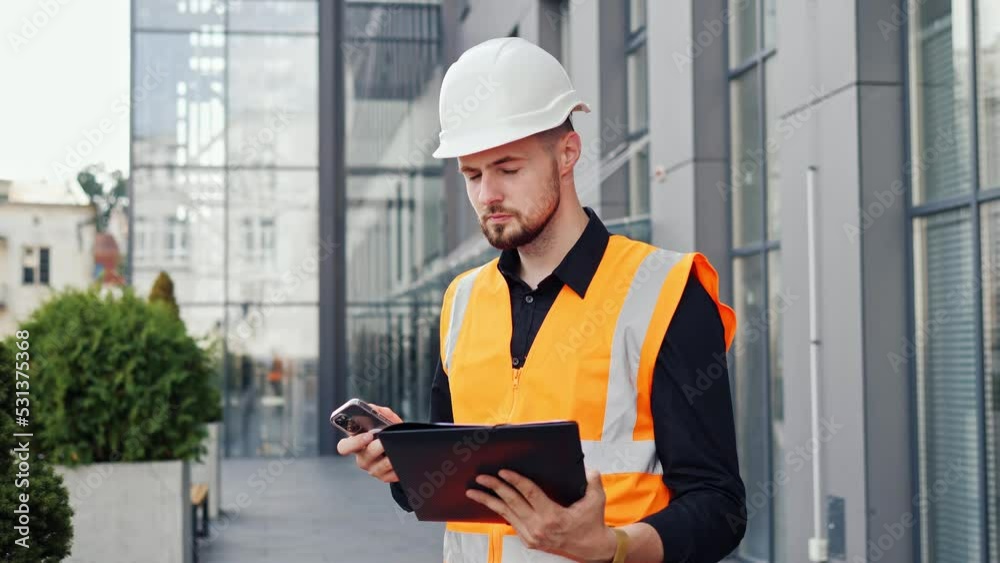 Serious thoughtful man architect designer holding document project sending typing message to contractor using mobile phone. Businessman discusses details of project with customer or boss outdoor. Serious thoughtful man architect designer holding document project sending typing message to contractor using mobile phone. Businessman discusses details of project with customer or boss outdoor.