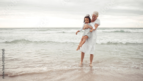 Grandmother, beach fun and child in happy bonding time together outside in nature. Elderly woman holding little girl in playful family bond at the ocean on holiday vacation in the outdoors #531376365