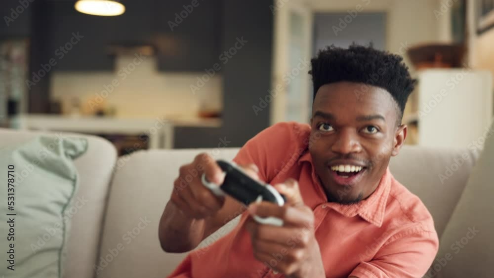 Online gaming, streaming and black man playing a video game while relaxing in his living room. Entertainment, tv and controller of an african gamer with energy and freedom sitting on the sofa at home Online gaming, streaming and black man playing a video game while relaxing in his living room. Entertainment, tv and controller of an african gamer with energy and freedom sitting on the sofa at home