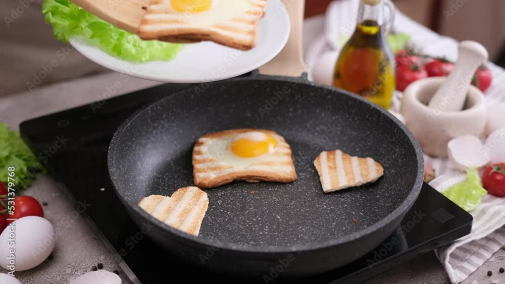 Woman cooking egg-in-a-hole toast on a hot frying pan at home kitchen Woman cooking egg-in-a-hole toast on a hot frying pan at home kitchen