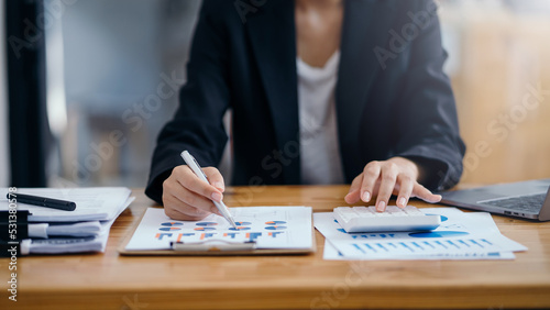 Close-up of the hand of a business woman using a calculator to check financial statement, balance sheet, income statement of a company. invoice document and important accounting document.