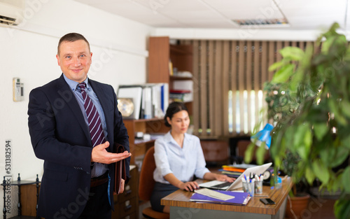 Portrait of smiling successful businessman inviting to modern office. Invitation to cooperation concept