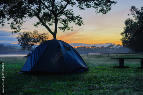 Camping dark blue tent on grass nature in early morning or during sunrise beautiful view, golden morning light, Summer camping. Tourism with natural, Healthy freedom lifestyle and mental recreation.