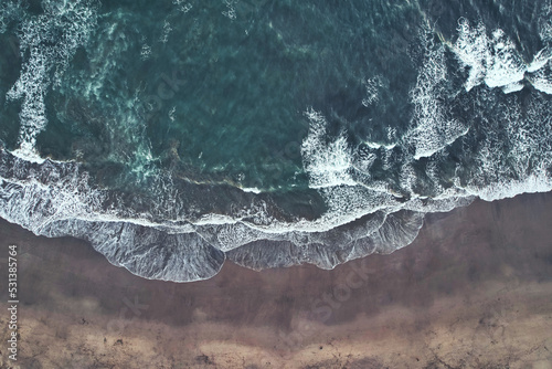 Big waves crushing on a sandy beach - blue green ocean captured with a drone - Canggu Bali