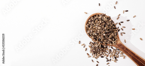 Thistle seeds in a wooden spoon on a white background, place for text, top view,baner