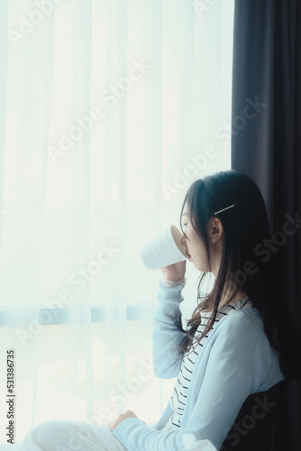 woman doing sitting at window after wake up with coffee mug