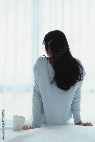 woman doing sitting on bed after wake up with coffee mug